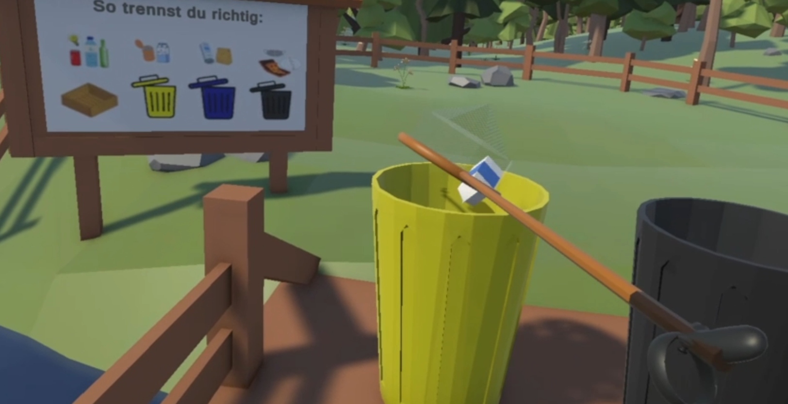 Ein Bild des Keschers, indem sich ein Milchkarton befindet. Der Kescher wird schräg über eine gelbe Mülltonne gehalten. Im Hintergrund ist eine Infotafel zu sehen, die die korrekte Mülltrennung verschiedener Gegenstände zeigt